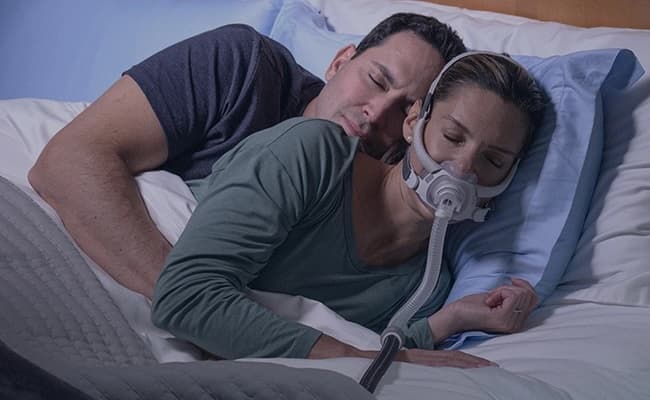 Para śpiąca w łóżku, pacjent w masce CPAP